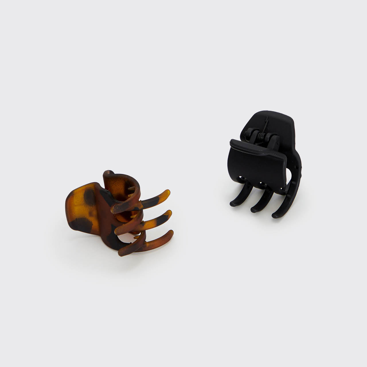 Black and tortoise medium claw clips shown from the back, highlighting the curved teeth and spring hinges