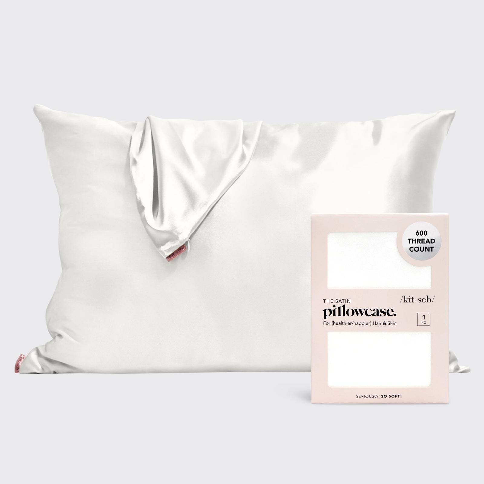 A white satin pillowcase on a pillow with a pink case in front of it