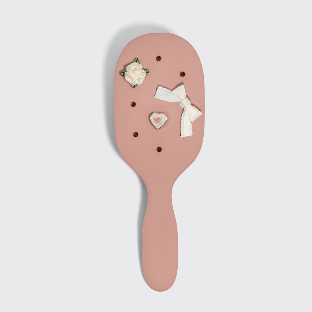 Pink hairbrush with decorative elements on a light gray background