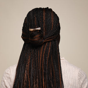 Person with braided hair styled in a bun against a neutral background