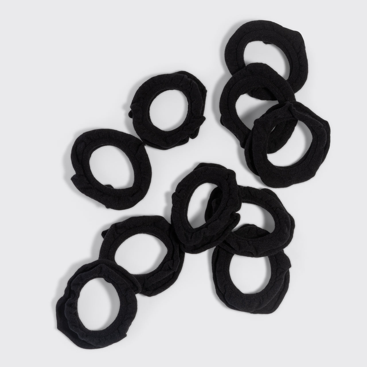 Black petal hair elastics scattered on a grey background