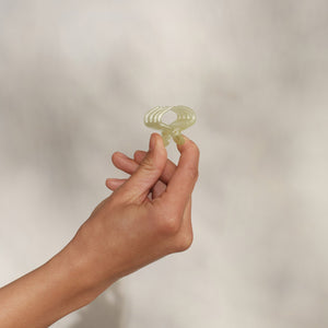 Hand holding single KITSCH Pearlized Cream Jelly Cloud Clip Mini pinched between fingers — close-up detail shot on cream background — mini claw clip showing jelly texture & ridged design in pearlized cream — All-Day Hold, Made from Recycled Materials — KITSCH Pearlized Cream & Butter Yellow Jelly Cloud Clips Mini 8pcs