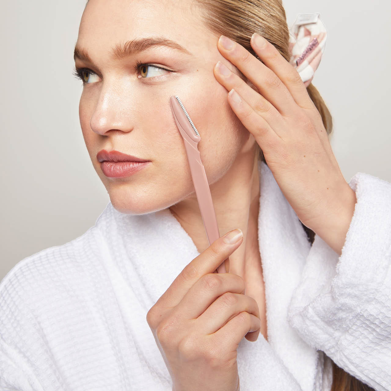 Model using the KITSCH Recycled Plastic Dermaplaner in Terracotta for facial exfoliation