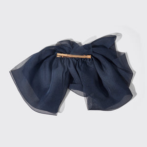 Navy blue bow hair clip on a light gray background