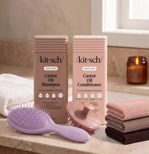 Kitsch Smoothing Castor Oil Shampoo and Conditioner bottles on a bathroom counter, with a free soft violet wet/dry brush, a terracotta scalp exfoliator, and the rosewood net sponge as aa free welcome kit.