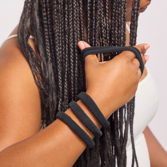 Model with box braids wearing Kitsch Recycled Nylon Thick Elastics in Black on wrist